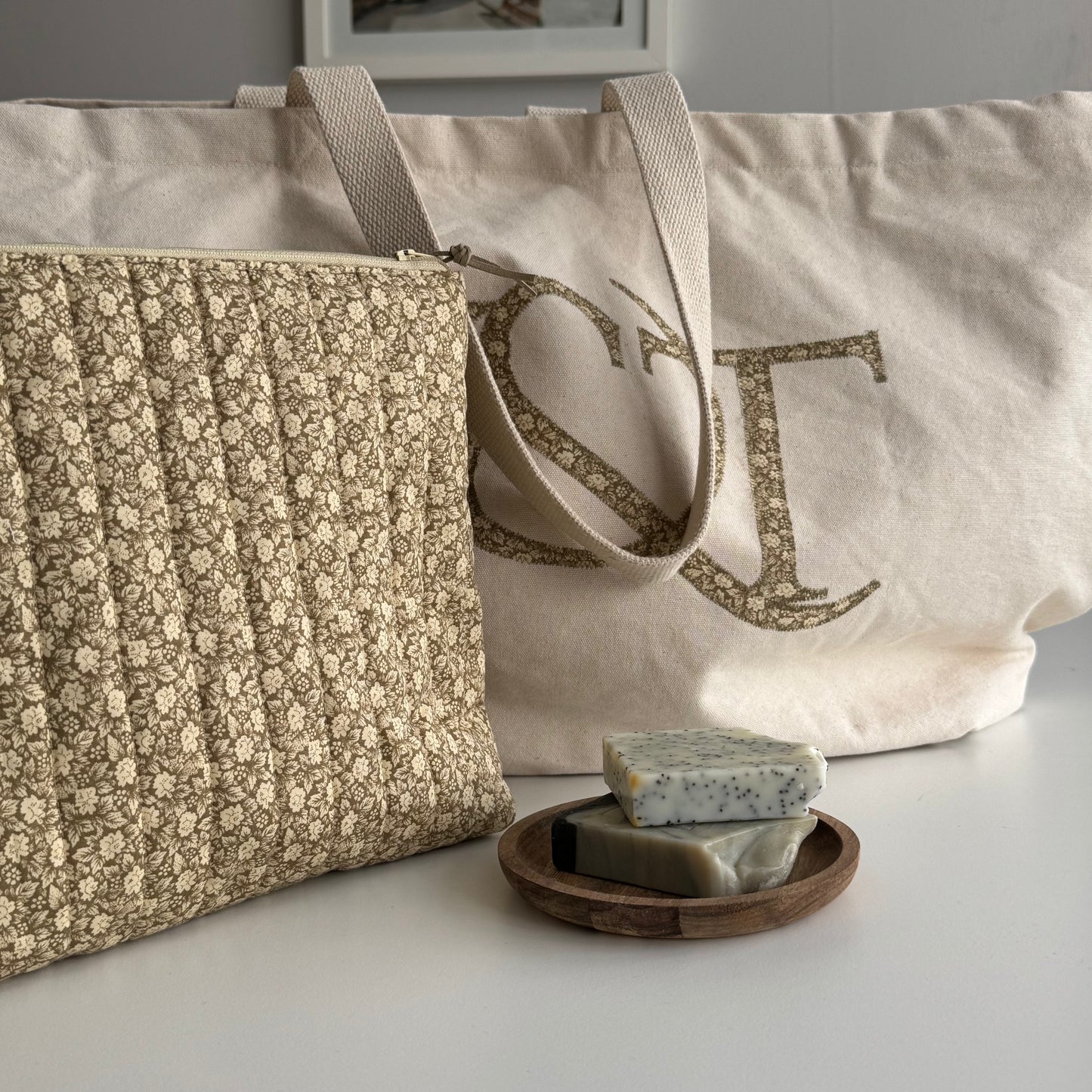 Two fabric bags with floral patterns and a wooden soap dish with soap bars on a light surface.