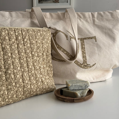 Two fabric bags with floral patterns and a wooden soap dish with soap bars on a light surface.