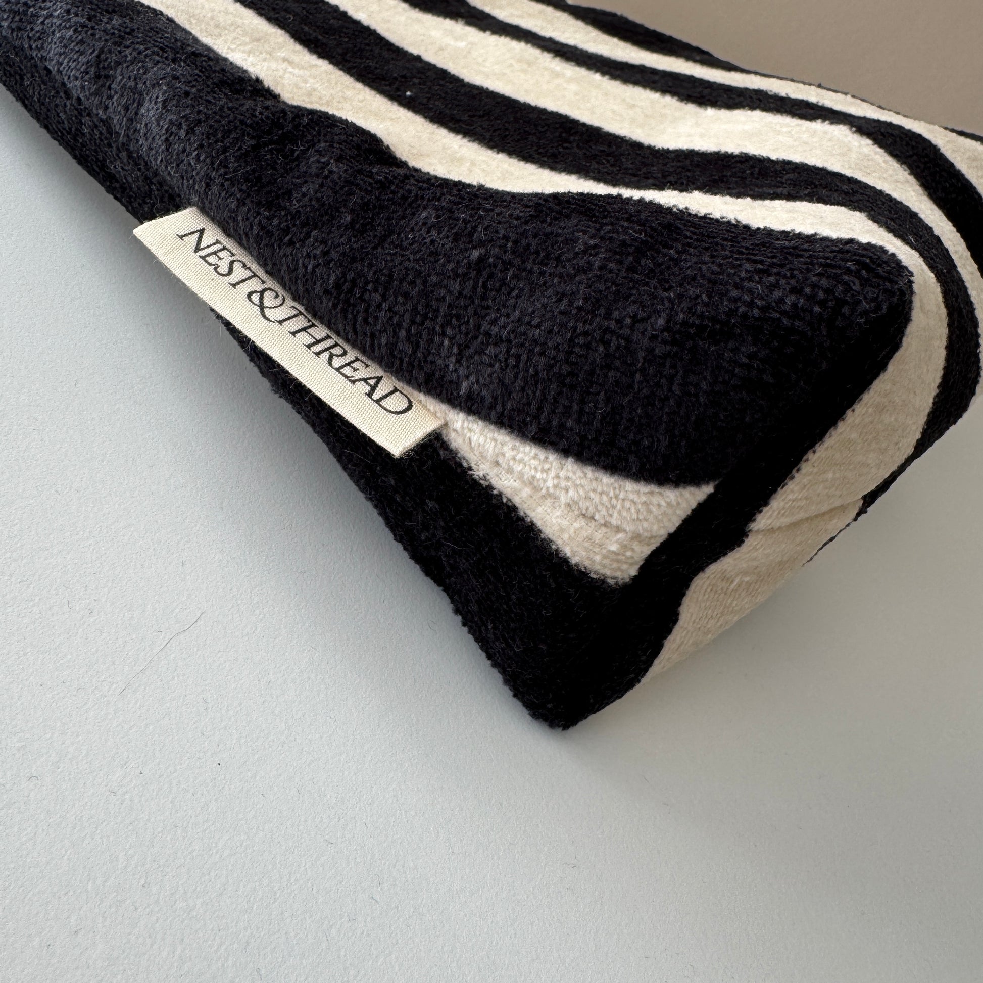 A close-up of a striped black and cream towelling cosmetic makeup bag