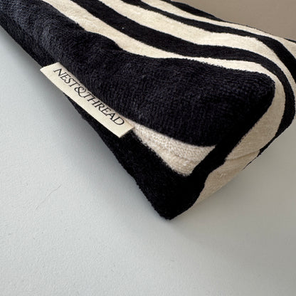 A close-up of a striped black and cream towelling cosmetic makeup bag